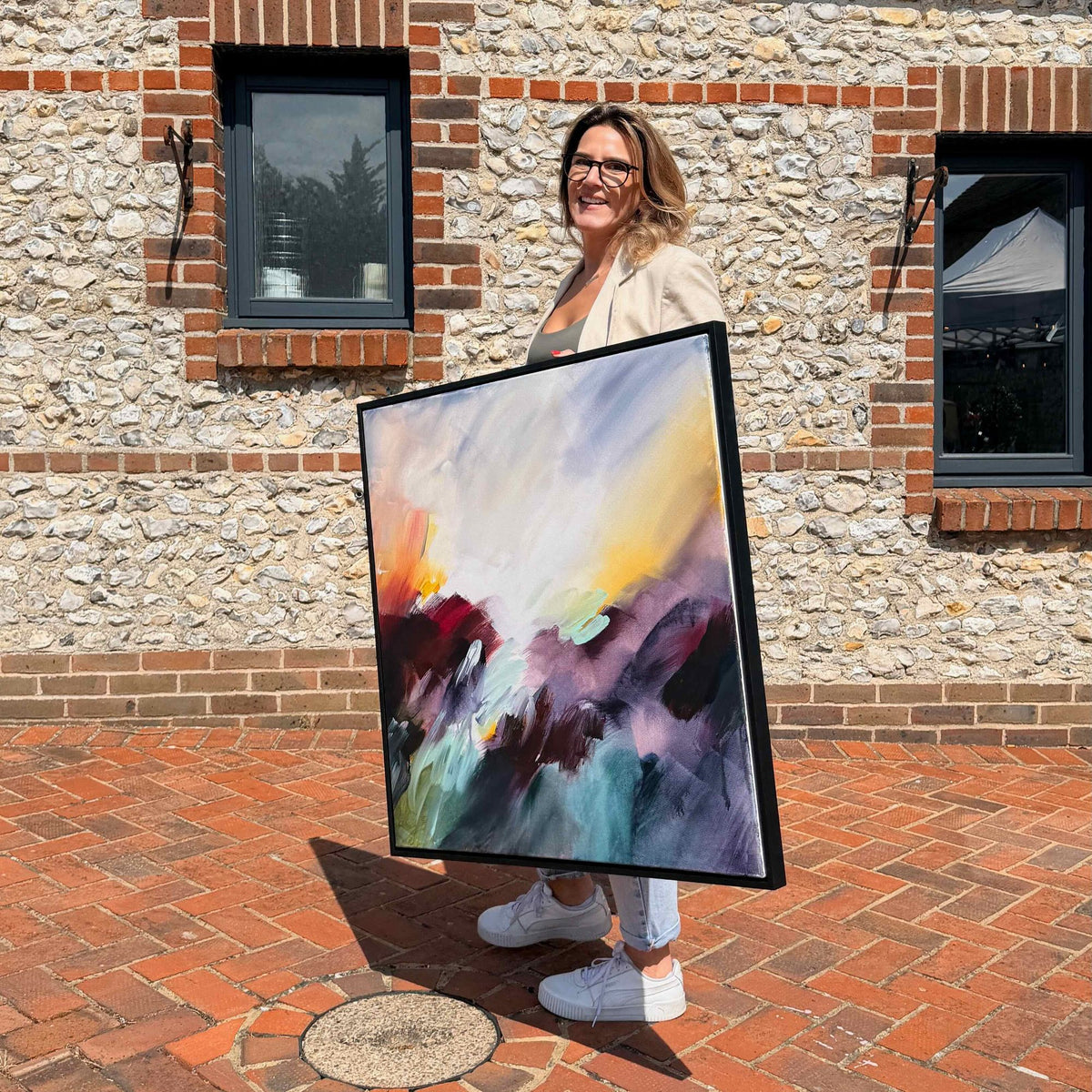Joanna Gilbert holding Where the Light Finds You, original abstract painting in a black frame