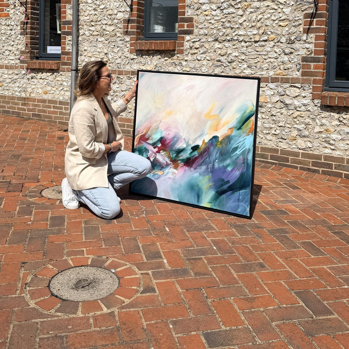 Joanna Gilbert kneeling beside Dreaming in Colour, her original abstract painting, at the Arundel Art Trail